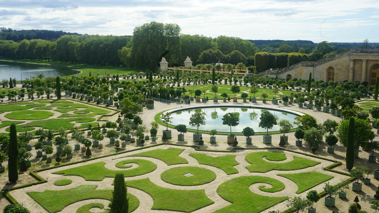 a large garden with a pond surrounded by trees