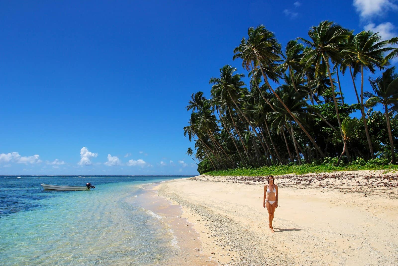 Young woman in bikini walking on a beach in Lavena village on Taveuni Island, Fiji.