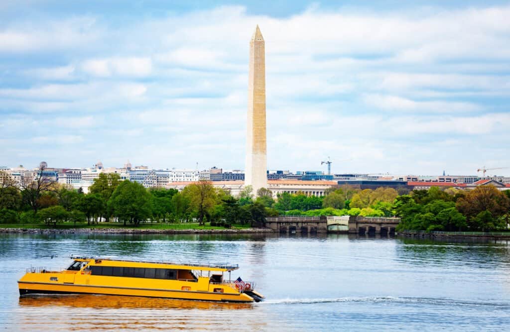 National mall Washington Monument obelisk over Potomac River with passing by yellow boat