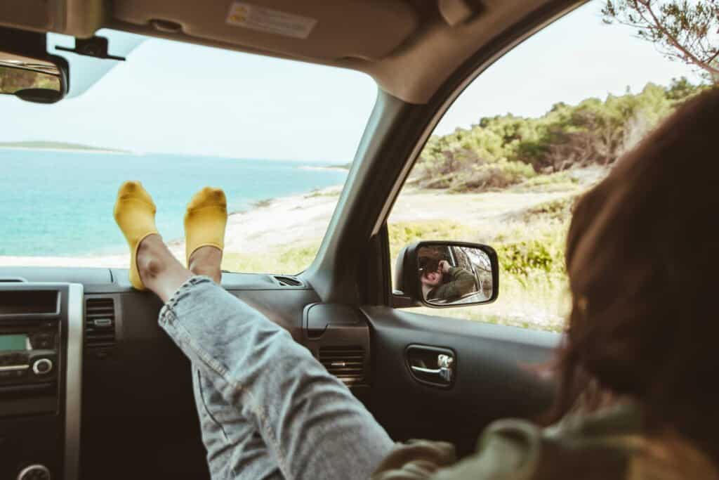 woman sitting in car looking at sea. reflection in mirror.