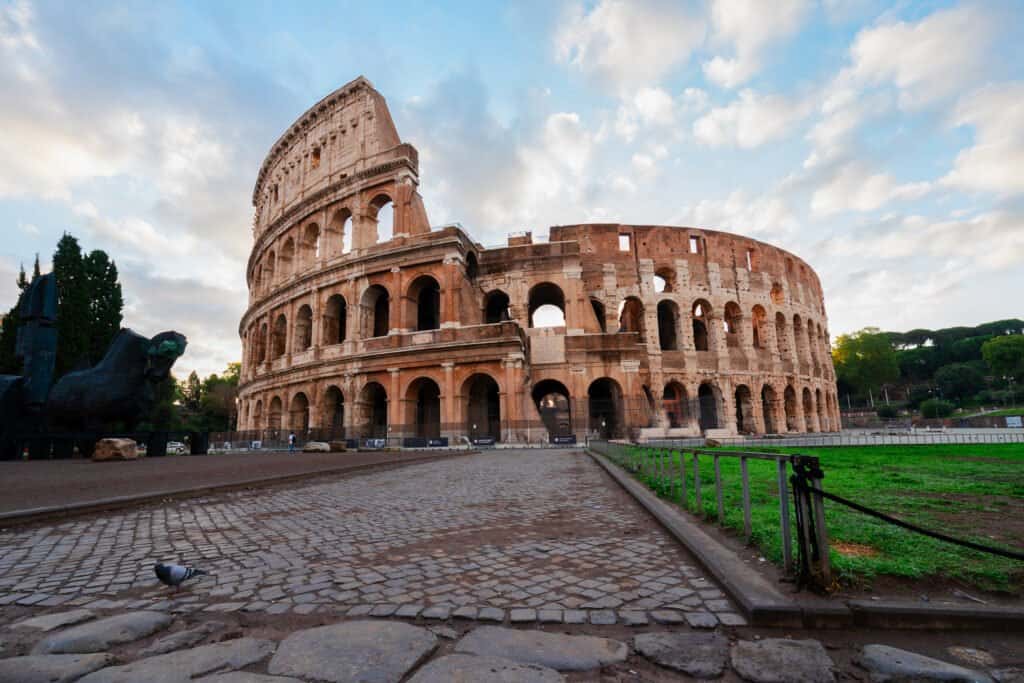 ruins of antique Colosseum with green grass lawn in sunise lights, Rome Italy