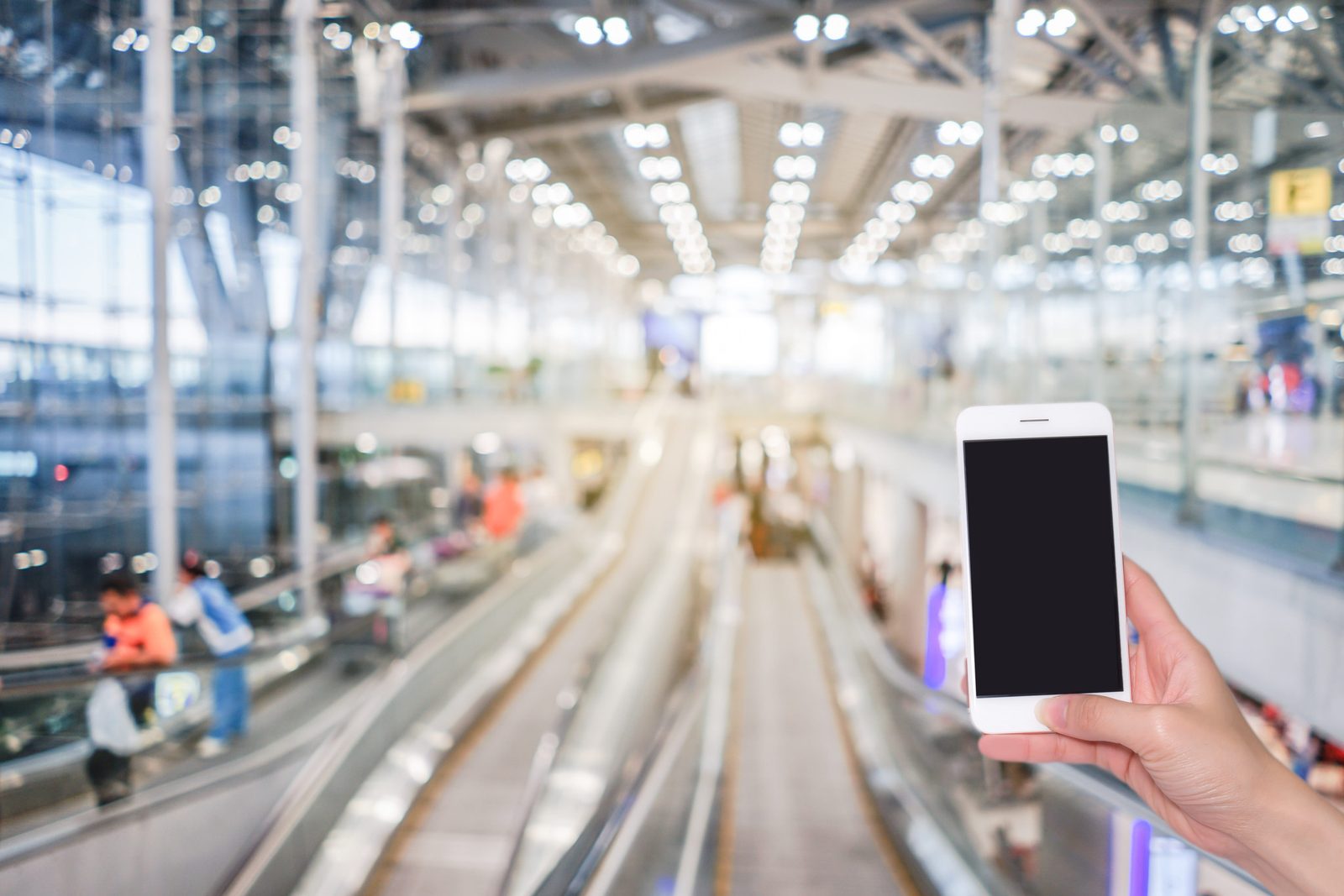A traveler holding a phone in a busy airport terminal