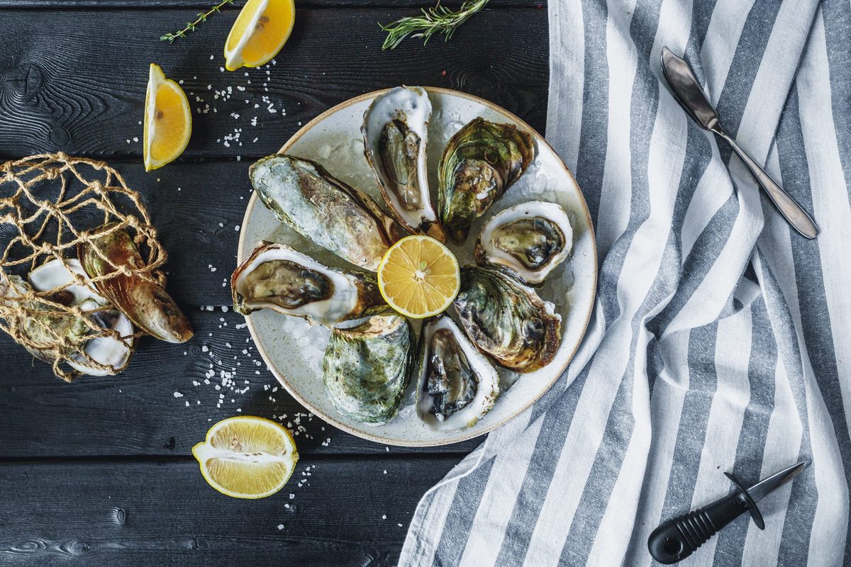 A plate of freshly shucked oysters on ice with lemon