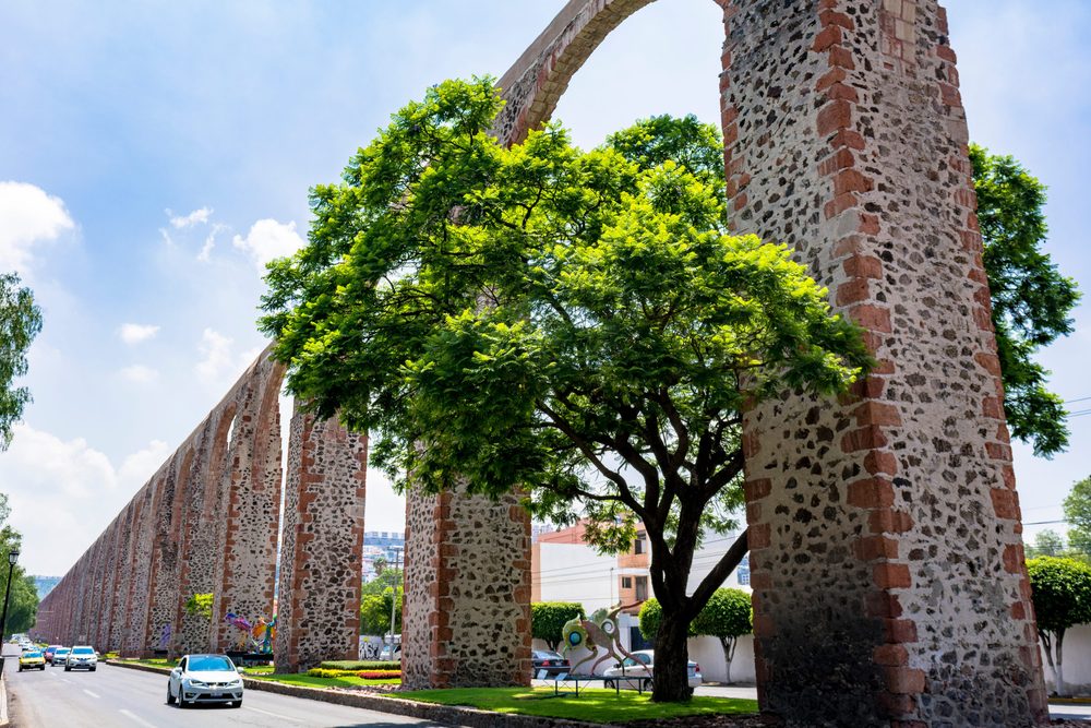 The Queretaro aqueduct running beside the road on its tall pink and grey stone piers