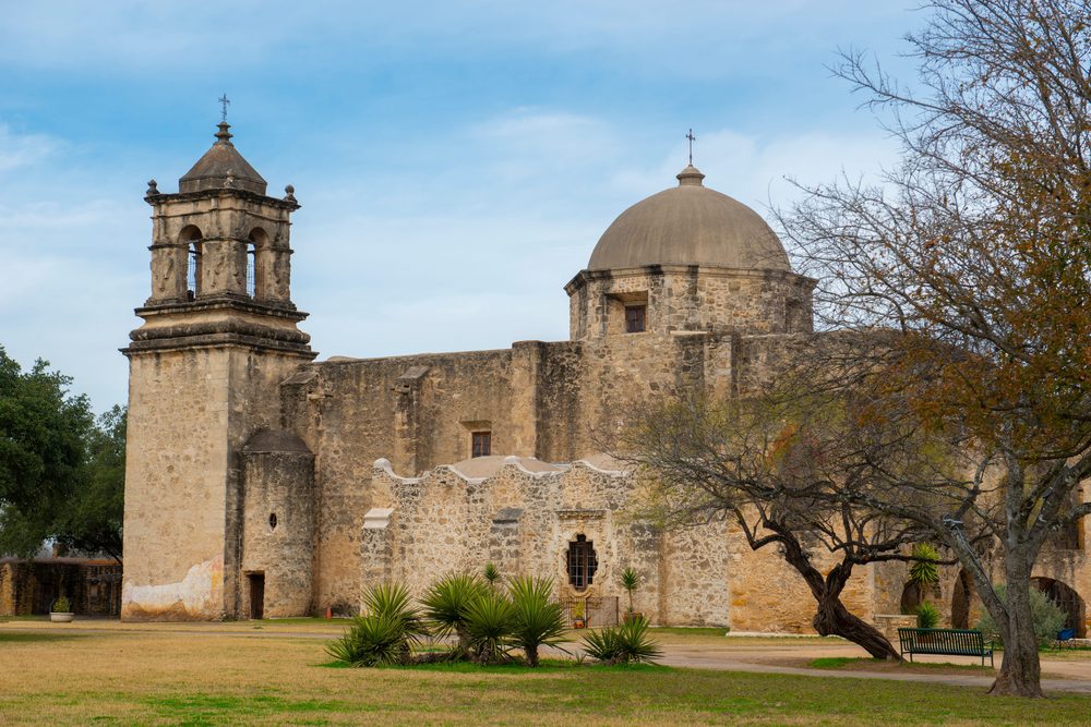 Mission San Jose in San Antonio, its stone bell tower and dome above the compound lawn