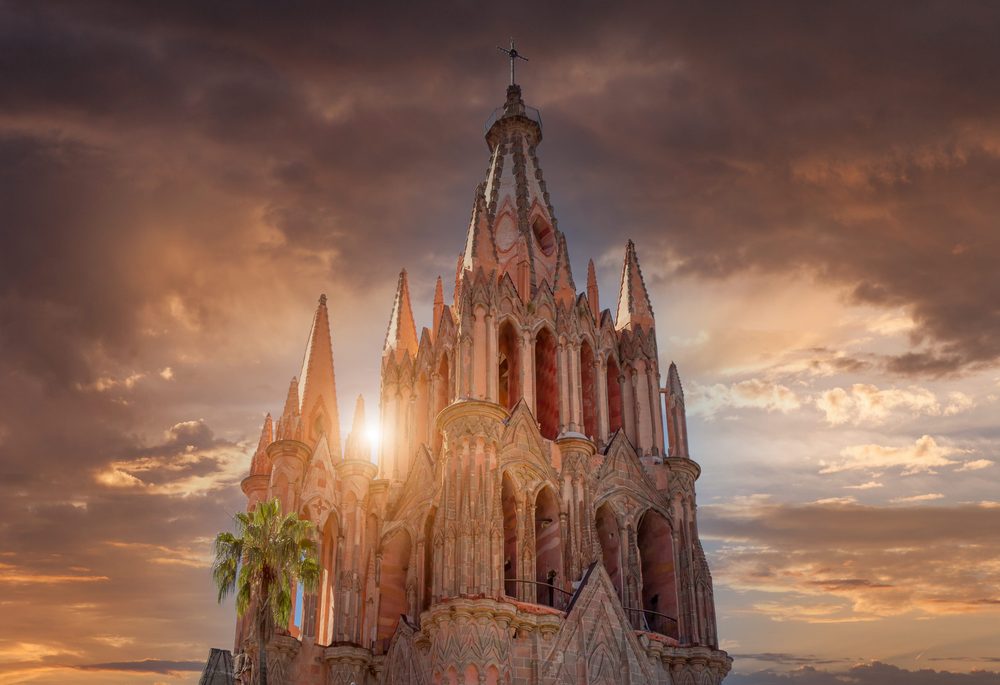 The pink neo-Gothic spires of the Parroquia de San Miguel Arcangel against an evening sky