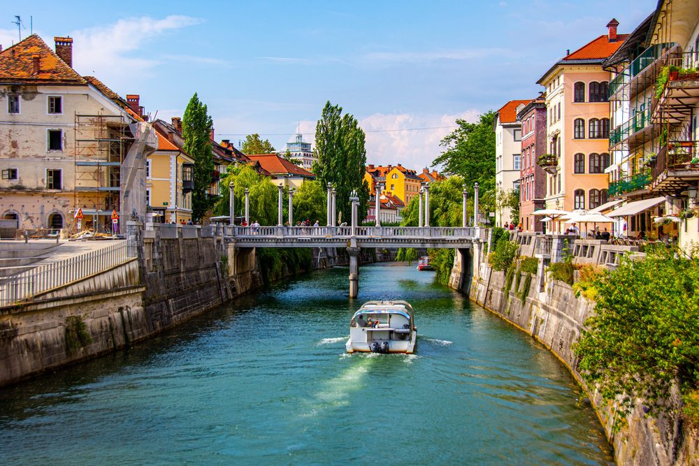 A boat on the Ljubljanica river passing the Cobblers' Bridge in central Ljubljana